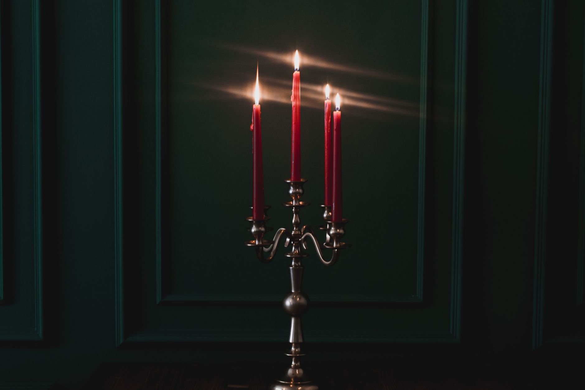 Candles burning on a candelabra in a dark room, casting a warm glow.