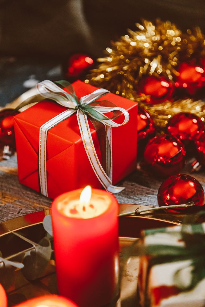 A ribboned gift box beside a candle, in warm candlelight.